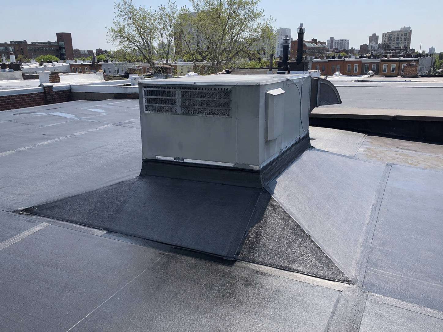 Tapered Roof Crickets Around HVAC Curbs on Philadelphia Flat Roofs shown in a realistic Philadelphia, PA residential construction setting.